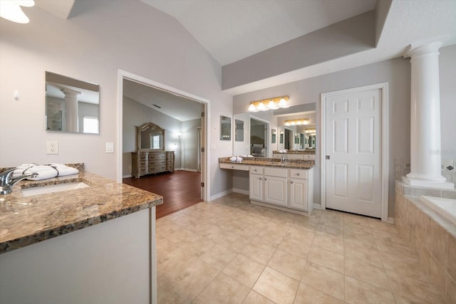 bathroom featuring tiled tub, vanity, ornate columns, wood-type flooring, and lofted ceiling