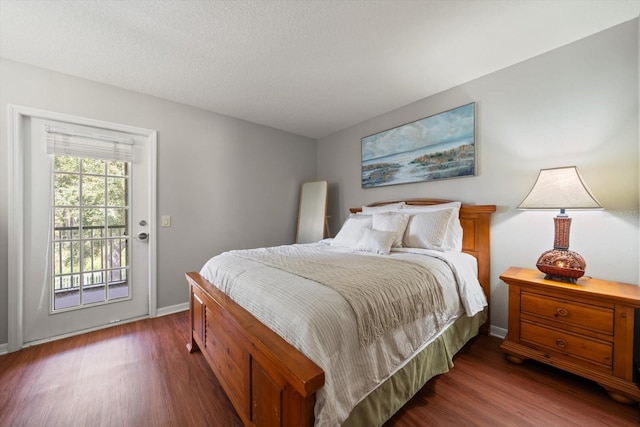 bedroom featuring a textured ceiling, access to exterior, and dark hardwood / wood-style flooring