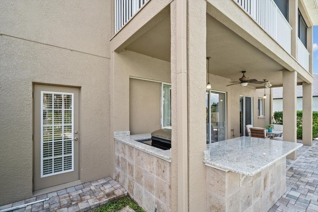 view of patio featuring a balcony, area for grilling, ceiling fan, and an outdoor kitchen