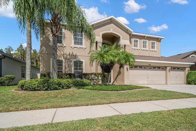 view of front of property with concrete driveway, an attached garage, a front lawn, and stucco siding