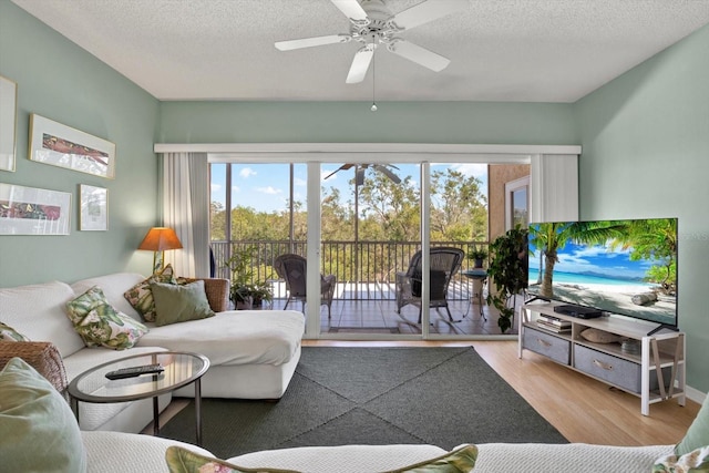 living room with a textured ceiling, light wood-type flooring, and ceiling fan