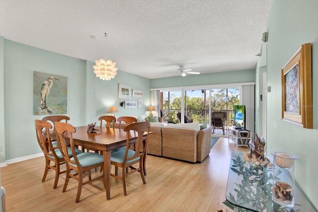 dining area with a textured ceiling, ceiling fan with notable chandelier, and light hardwood / wood-style floors