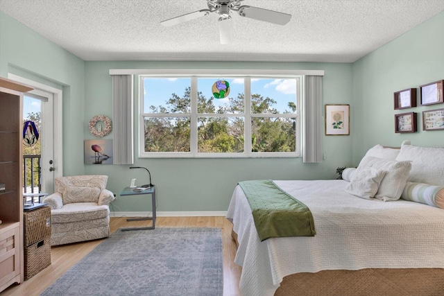 bedroom featuring ceiling fan, multiple windows, light hardwood / wood-style floors, and access to exterior