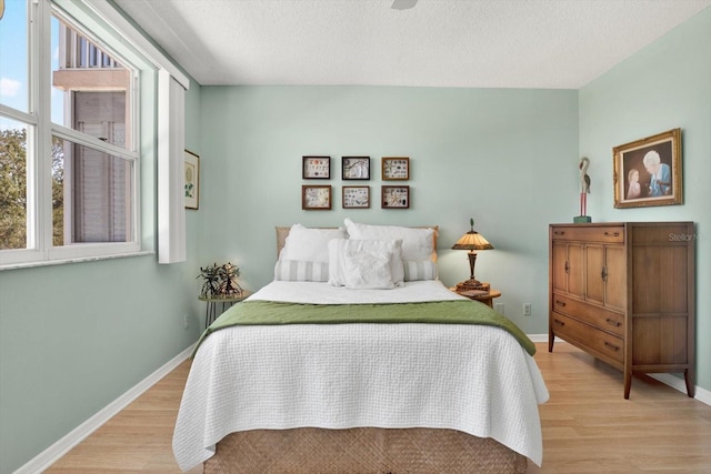 bedroom with a textured ceiling and light wood-type flooring