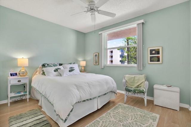 bedroom with ceiling fan, a textured ceiling, and light wood-type flooring