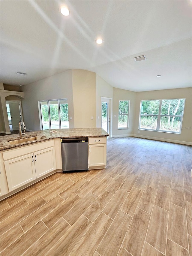 kitchen featuring light wood-type flooring, sink, vaulted ceiling, light stone countertops, and stainless steel dishwasher