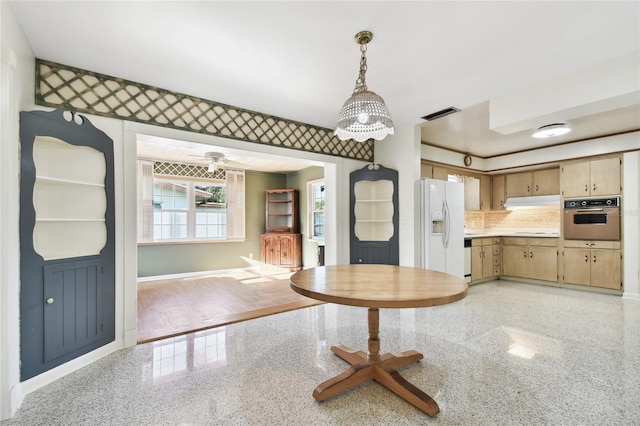 kitchen featuring pendant lighting, white refrigerator with ice dispenser, tasteful backsplash, ceiling fan with notable chandelier, and stainless steel oven