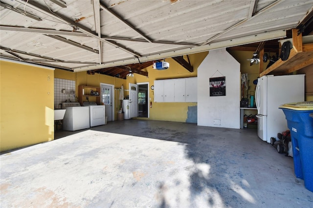 garage with water heater, white fridge, a garage door opener, sink, and washing machine and clothes dryer