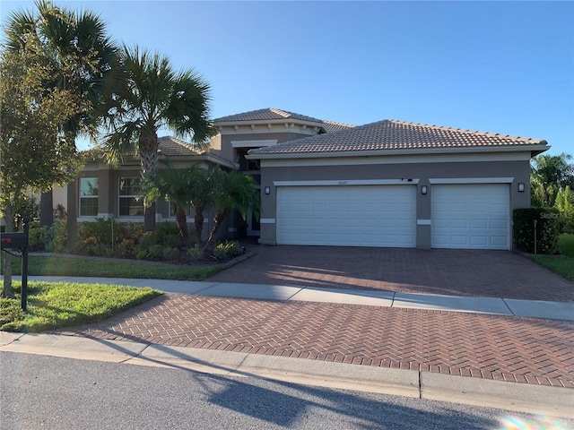 16015 Cape Coral Dr, Wimauma, FL 33598 - view of front of house featuring decorative driveway, stucco siding, an attached garage, and a tile roof