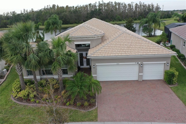 view of front of property with a garage, french doors, and a water view