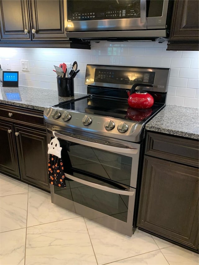 kitchen with light stone counters, dark brown cabinets, tasteful backsplash, and appliances with stainless steel finishes