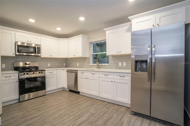 kitchen with appliances with stainless steel finishes, white cabinets, and light wood-type flooring