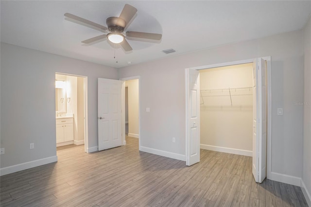 unfurnished bedroom featuring a closet, ceiling fan, a spacious closet, and light wood-type flooring