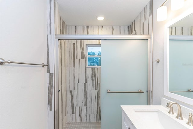 bathroom with vanity, a shower with shower door, and a textured ceiling