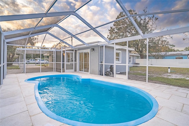 pool at dusk featuring a patio and glass enclosure