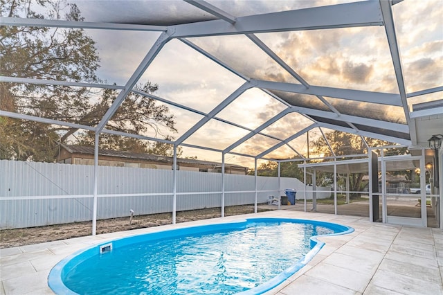 pool at dusk with a patio area and glass enclosure