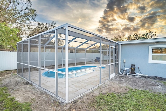 pool at dusk featuring a patio and a lanai