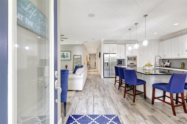 kitchen featuring light wood-type flooring, tasteful backsplash, sink, white cabinetry, and stainless steel appliances