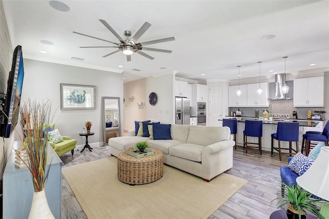 living room featuring ceiling fan, light hardwood / wood-style flooring, and crown molding