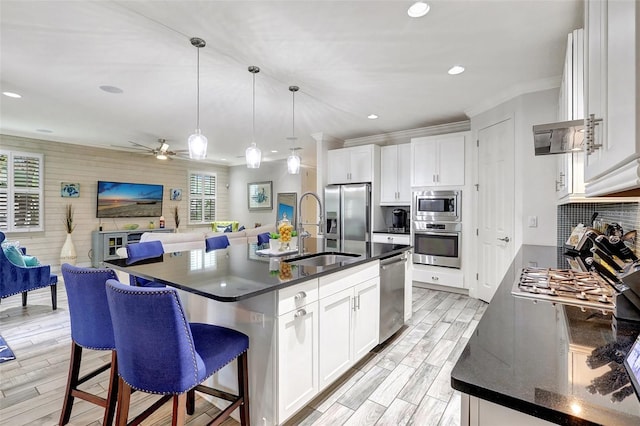 kitchen with appliances with stainless steel finishes, a center island with sink, white cabinetry, and sink