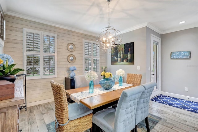 dining area featuring light wood-type flooring, crown molding, wood walls, and an inviting chandelier