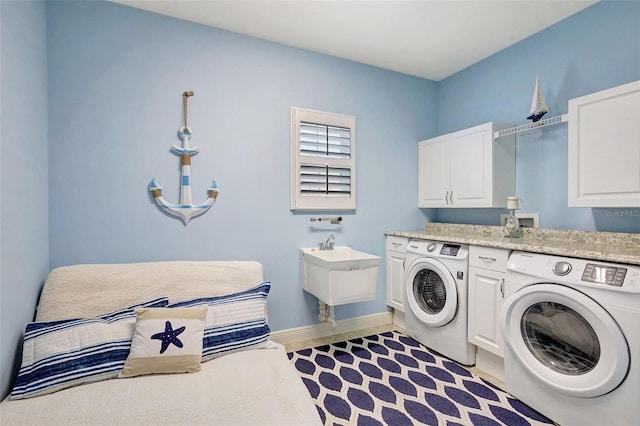 clothes washing area featuring cabinets, washer and dryer, and sink