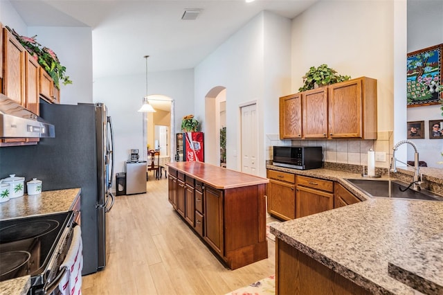 kitchen with a center island, range, sink, light hardwood / wood-style flooring, and decorative light fixtures