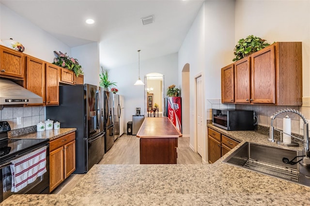 kitchen with light hardwood / wood-style floors, sink, backsplash, black appliances, and extractor fan