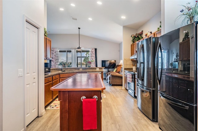 kitchen featuring light wood-type flooring, a center island, sink, vaulted ceiling, and black appliances