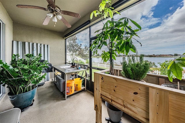 sunroom / solarium featuring ceiling fan, sink, and a water view