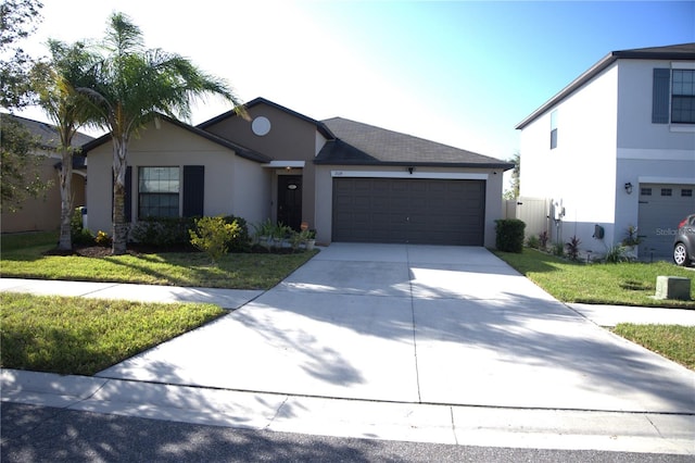 single story home with a garage, a front lawn, concrete driveway, and stucco siding