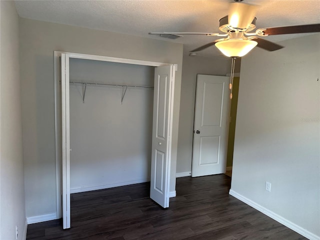 unfurnished bedroom featuring a textured ceiling, ceiling fan, dark hardwood / wood-style floors, and a closet