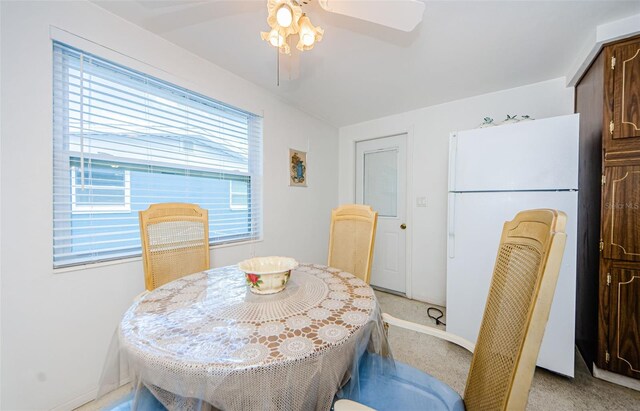 carpeted dining space featuring a healthy amount of sunlight and ceiling fan