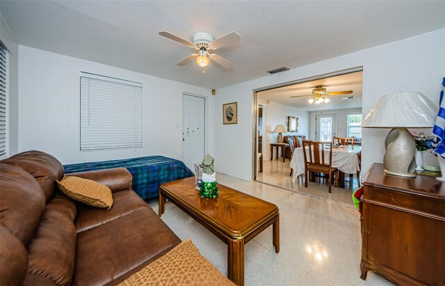 living room with ceiling fan and a textured ceiling