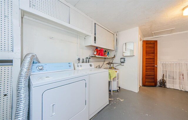 laundry area with washing machine and clothes dryer and a textured ceiling