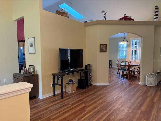 living room featuring dark hardwood / wood-style flooring, a skylight, and high vaulted ceiling