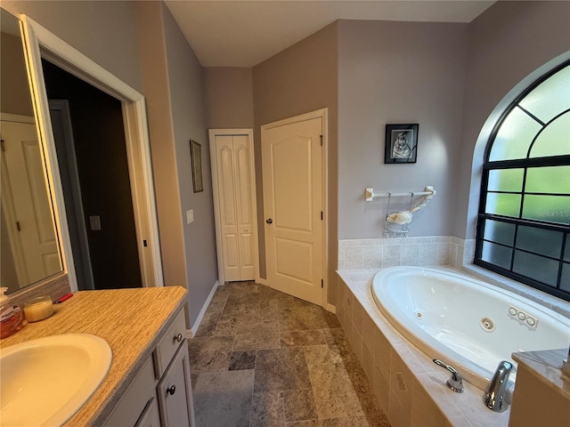 bathroom featuring tiled tub and vanity