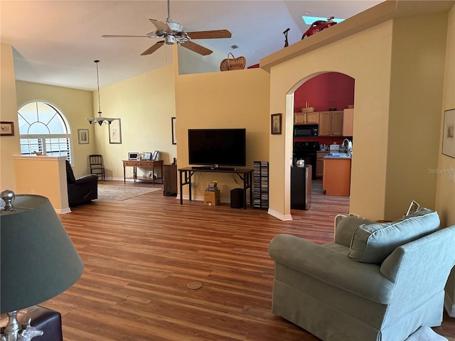 living room featuring ceiling fan with notable chandelier, sink, high vaulted ceiling, and hardwood / wood-style flooring