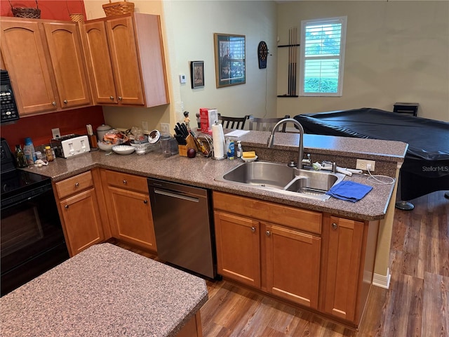 kitchen with sink, hardwood / wood-style floors, kitchen peninsula, and black appliances