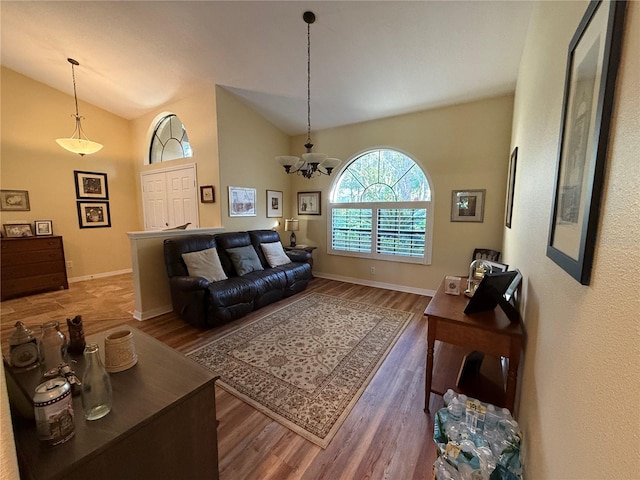 living room featuring wood-type flooring, a notable chandelier, and vaulted ceiling