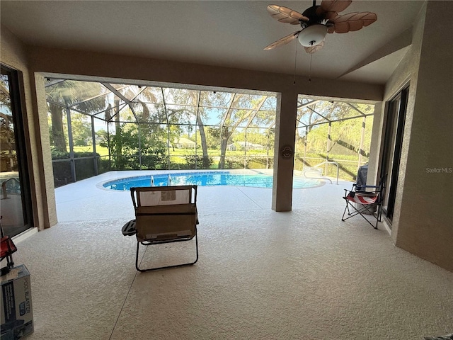 view of swimming pool with ceiling fan, glass enclosure, and a patio