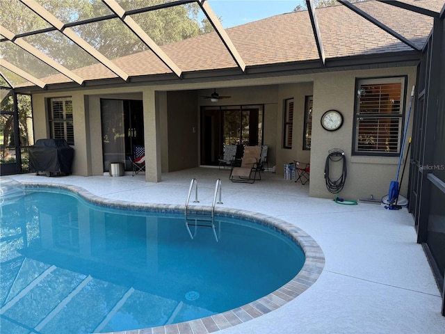 view of pool with ceiling fan, grilling area, glass enclosure, and a patio area