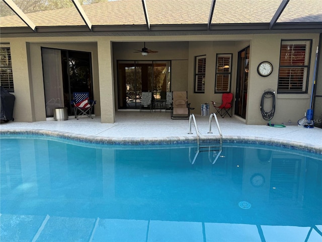 view of swimming pool featuring a patio, glass enclosure, and ceiling fan