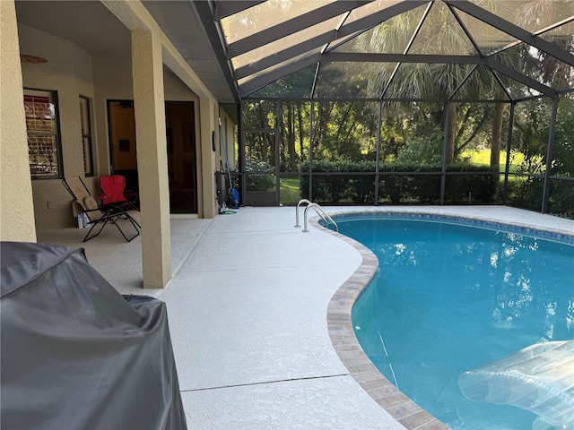 view of swimming pool featuring glass enclosure and a patio