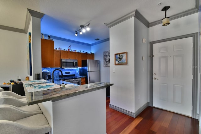 kitchen with tasteful backsplash, a kitchen bar, stainless steel appliances, ornamental molding, and dark hardwood / wood-style floors