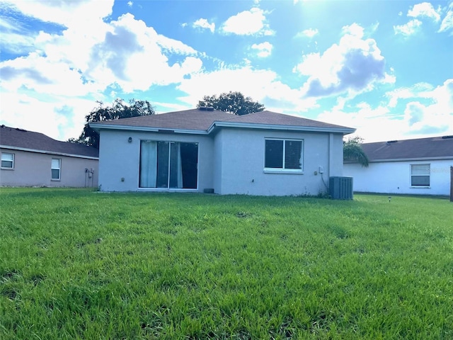 rear view of property with cooling unit and a yard