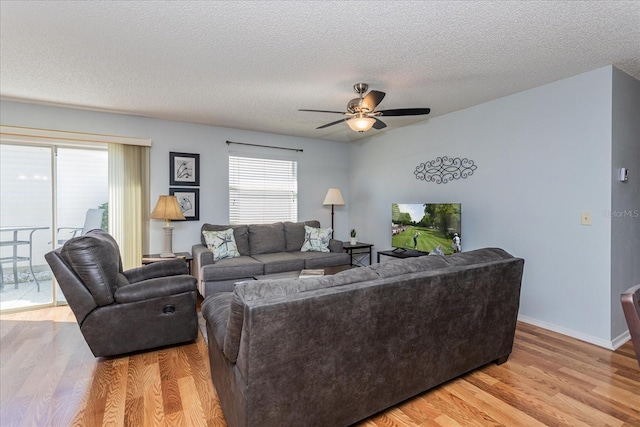 living room with ceiling fan, light hardwood / wood-style flooring, and a textured ceiling