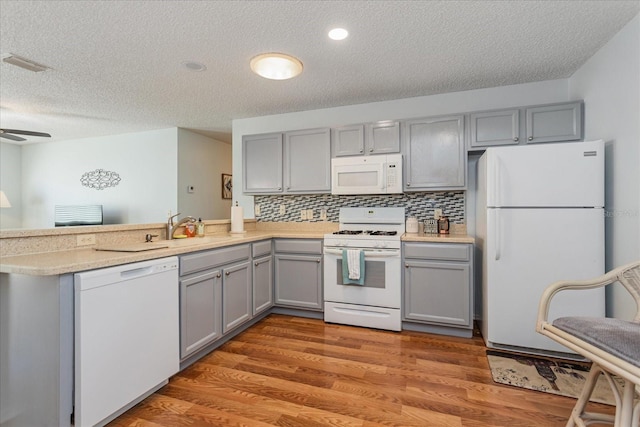 kitchen with gray cabinetry, wood-type flooring, white appliances, ceiling fan, and sink