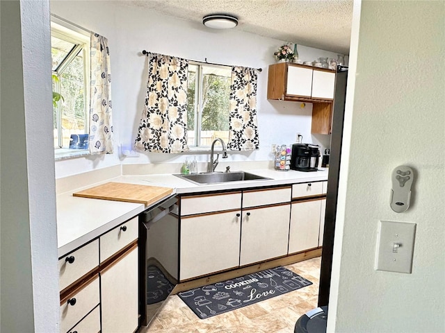 kitchen with dishwasher, sink, white cabinetry, and a textured ceiling