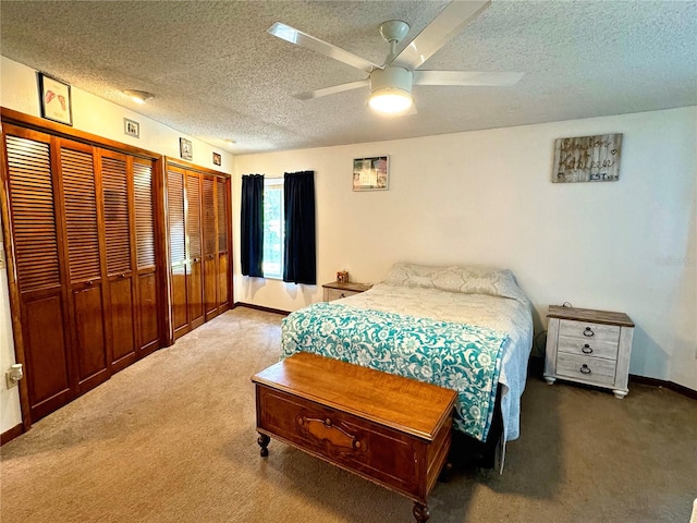 bedroom with multiple closets, ceiling fan, dark carpet, and a textured ceiling